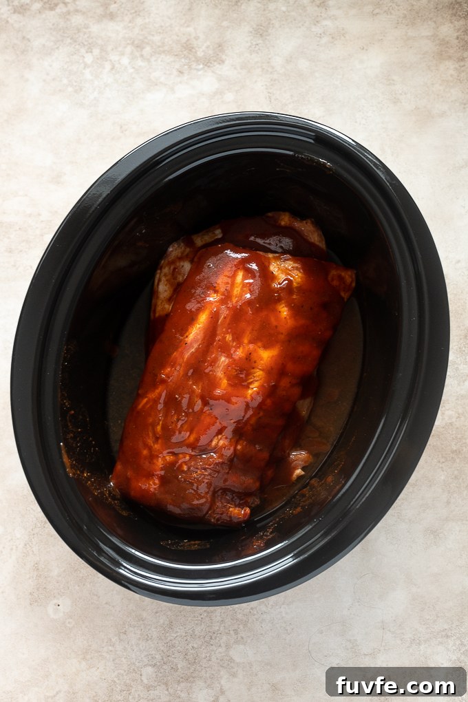 Fall-Off-the-Bone Slow-Cooker Baby Back Ribs 6 Baby back ribs smothered in bbq sauce in slow cooker.