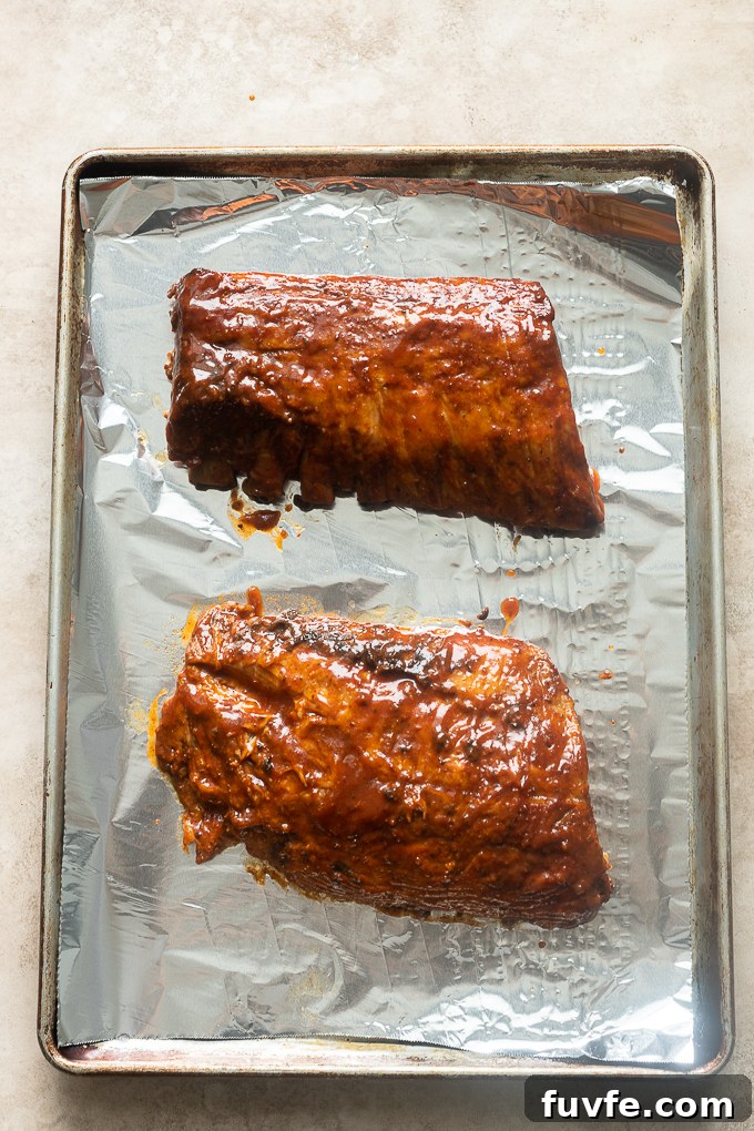 Fall-Off-the-Bone Slow-Cooker Baby Back Ribs 8 Cooked ribs with additional bbq sauce before broiling.