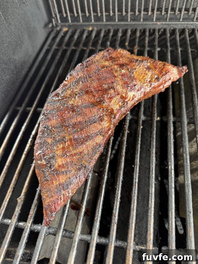Tri tip roast cooking over indirect heat on grill.