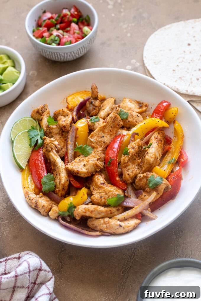 Air Fryer Chicken Fajitas Recipe: 20-Minute Dinner 3 Air fryer chicken fajitas in a bowl with cilantro leaves.