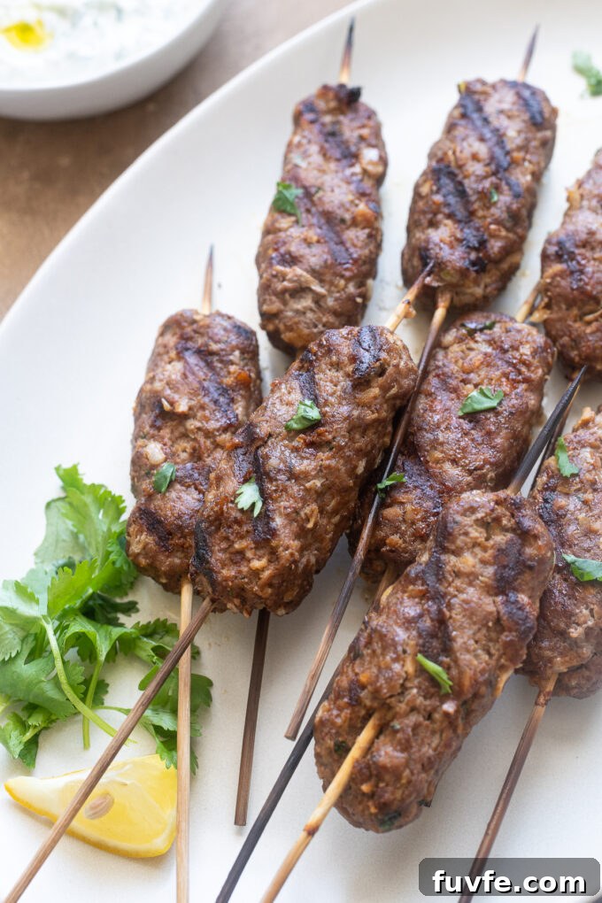 Grilled lamb kofta with wooden skewers on serving platter.