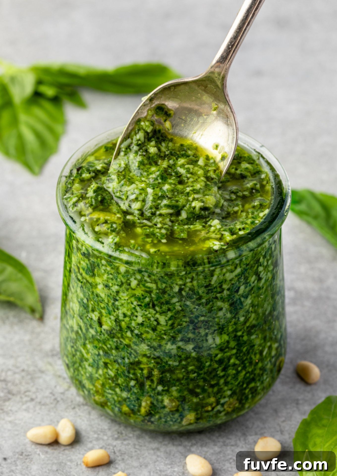 Basil pesto in a jar with spoon digging in