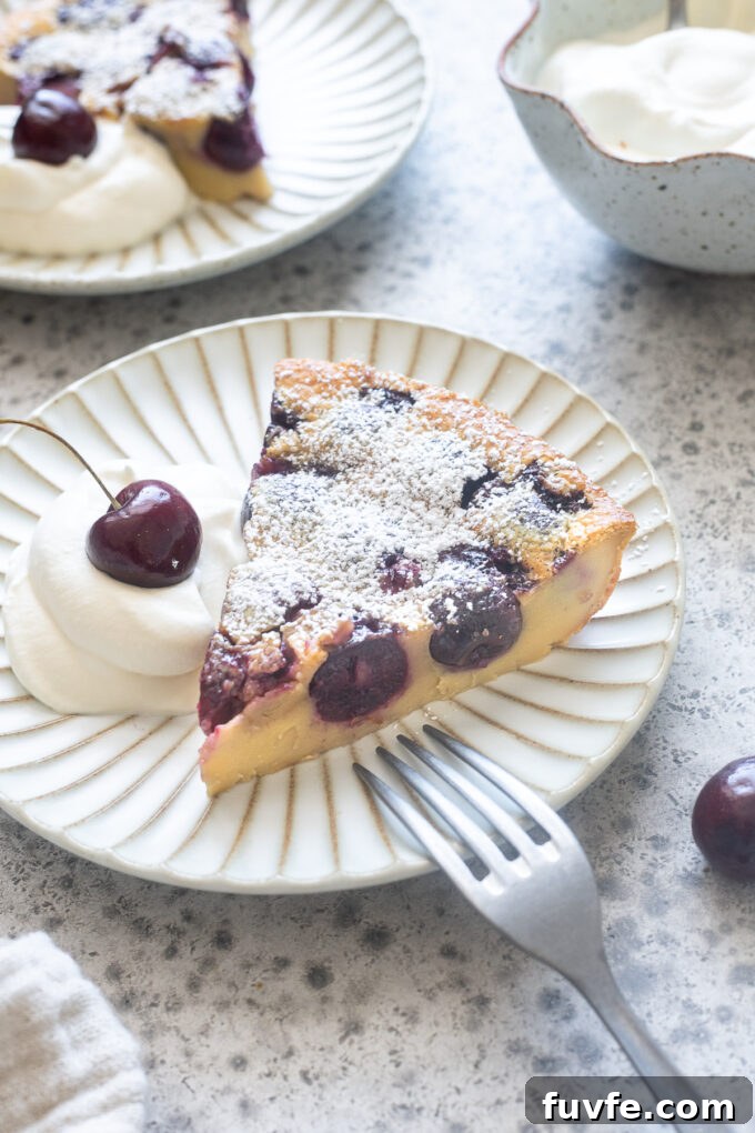 Slice of Cherry clafoutis on a plate with whipped cream.