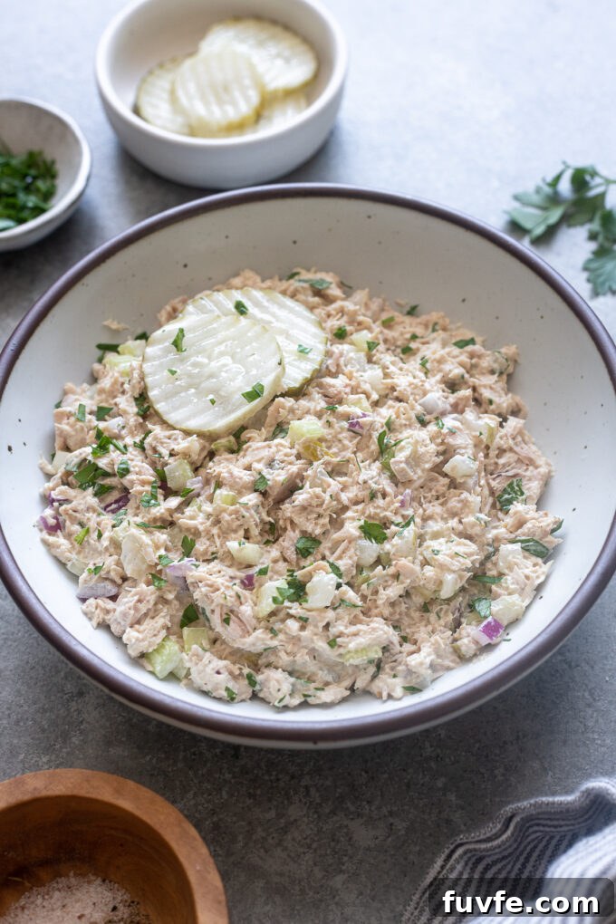 Dill pickle tuna salad with two pickle chips and parsley garnish.