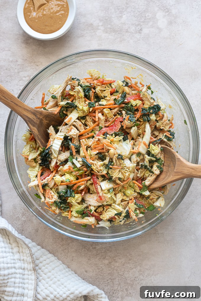 Thai chicken salad with peanut dressing tossed in a mixing bowl.