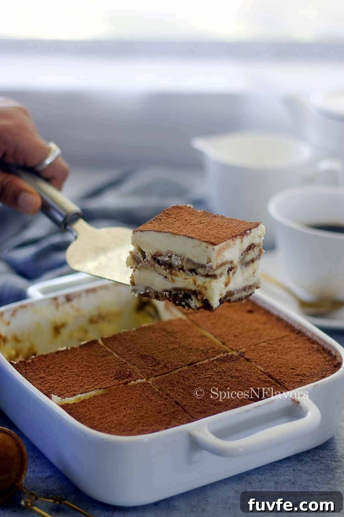 Eggless Tiramisu Recipe with Homemade Ladyfingers 10 slice of tiramisu held using a serving knife to show the layers within