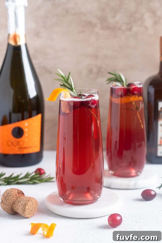 Poinsettia Cocktail Recipe: Cranberry Champagne Holiday Drink 2 Poinsettia Cocktails garnished with cranberries and orange twist.