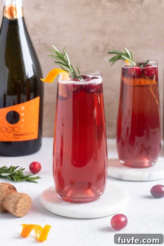 Poinsettia Cocktail Recipe: Cranberry Champagne Holiday Drink 12 Cranberry champagne cocktails with orange twist, cranberries and rosemary garnishes.