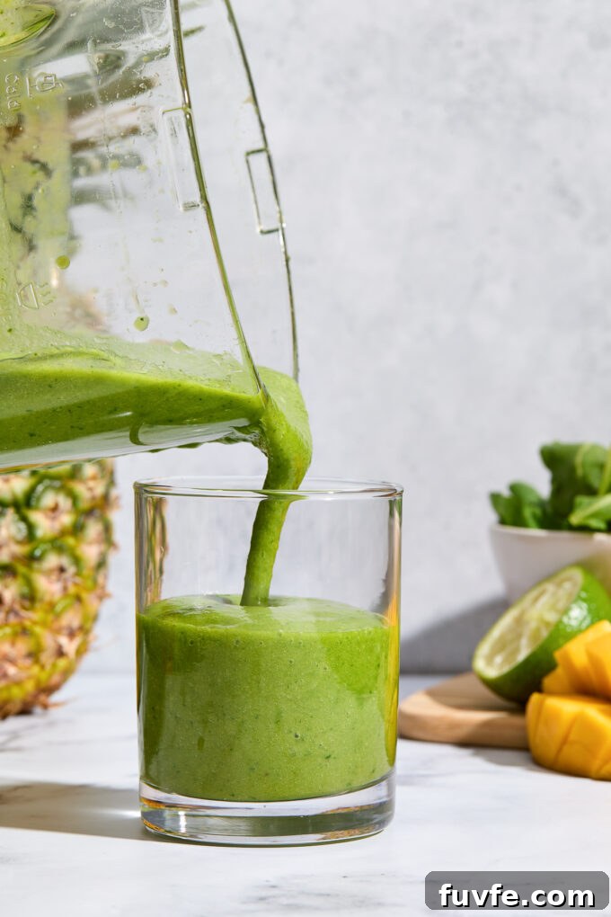Kale and fruit smoothie pouring into a glass.