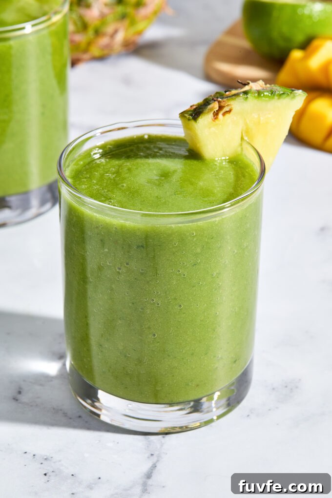 Mango Kale Smoothie in a glass with pineapple wedge.