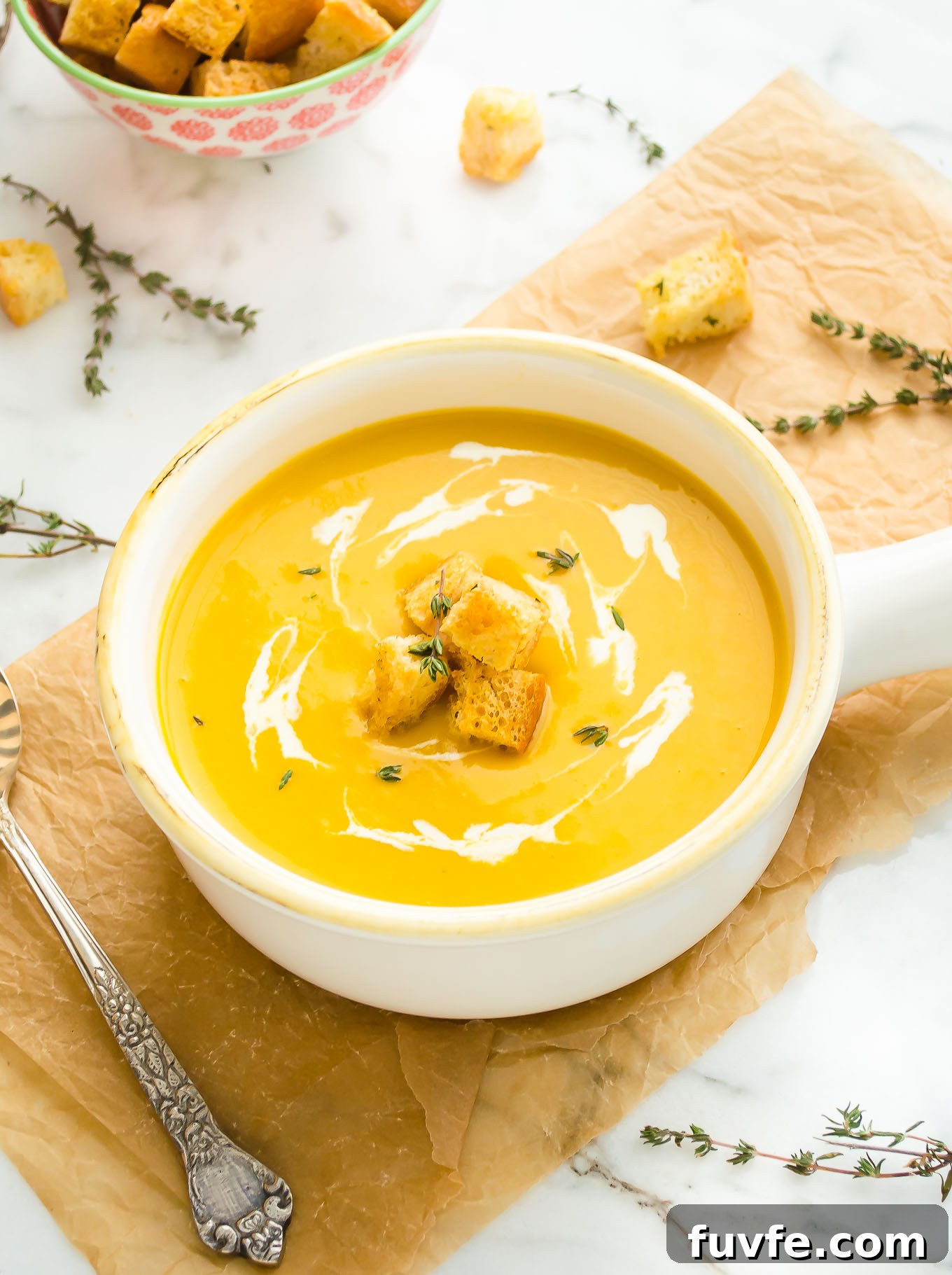 Butternut squash soup in a white bowl with croutons on top