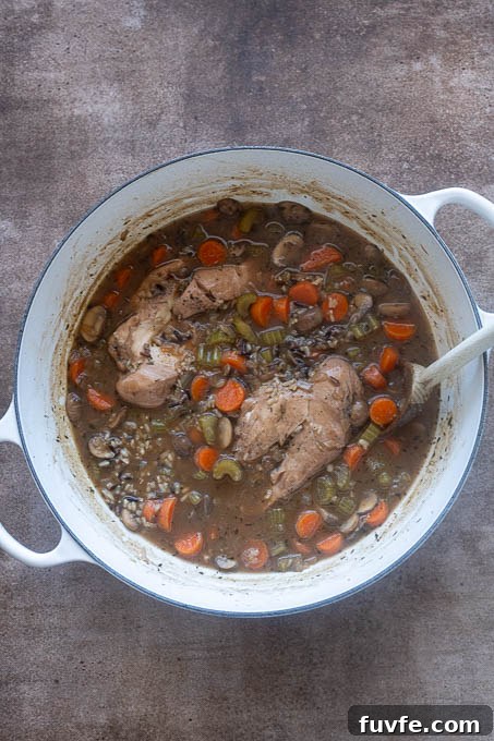 Finished chicken and wild rice soup in pot with chicken breasts whole.