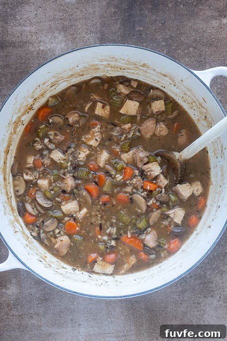 Chicken and wild rice soup in pot with chopped chicken breast.