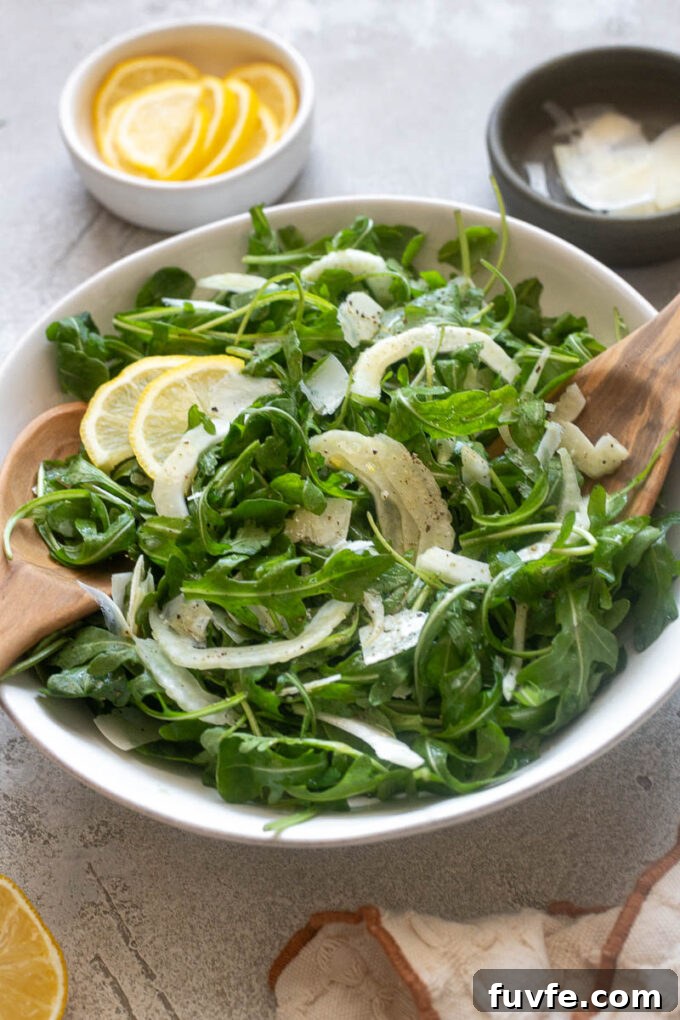 Simple fennel salad in a bowl with salad servers.