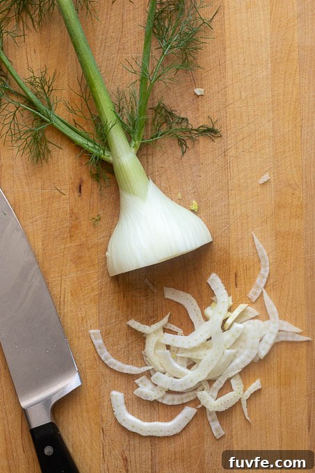 Shaved fennel on a cutting board for fennel arugula salad.