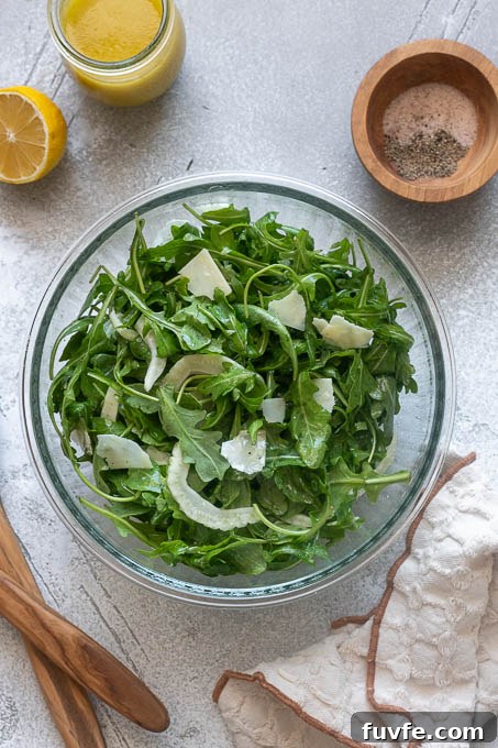 Fennel and arugula salad with parmesan tossed in a bowl.