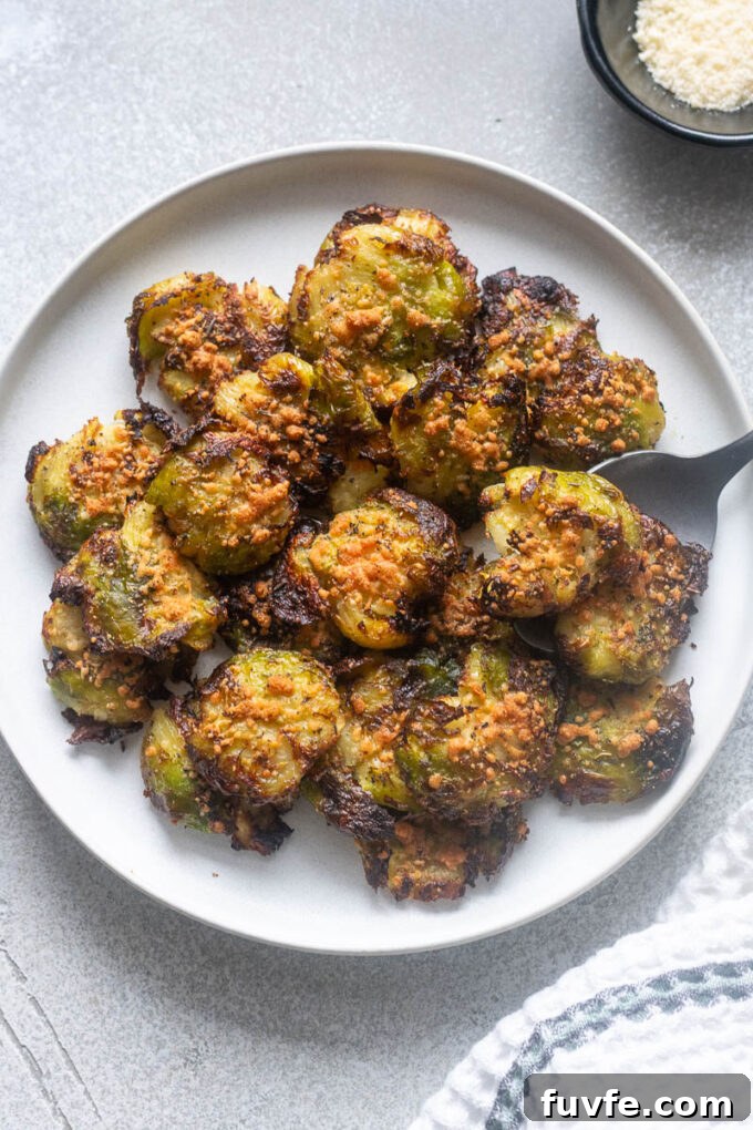 Smashed brussels sprouts on a plate with a serving spoon.