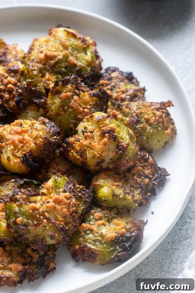 Close up of smashed brussels sprouts with parmesan on a plate.