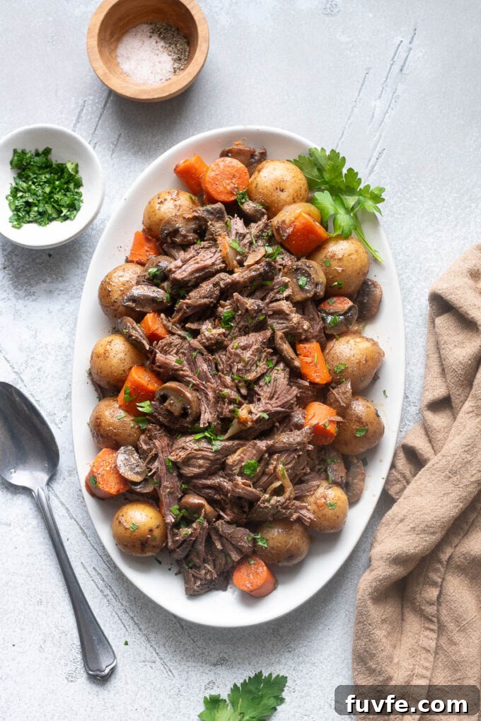 Slow cooker pot roast on a platter with potatoes and carrots.