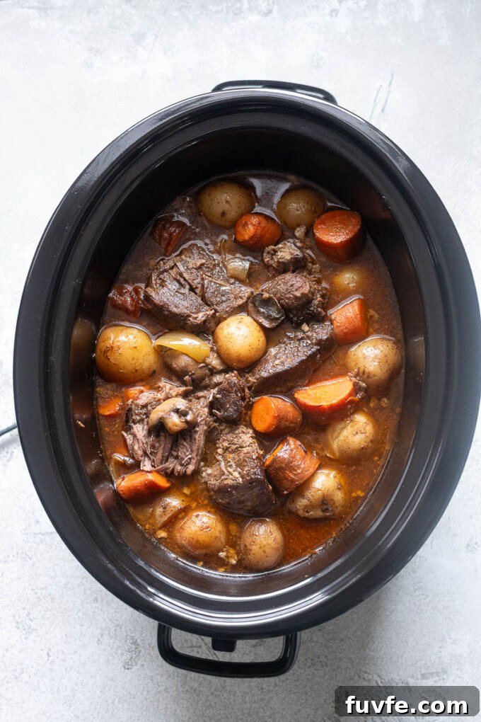 Beef pot roast in the slow cooker with mushrooms, potatoes and carrots.