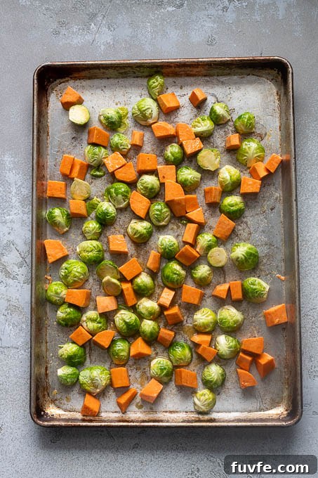 Roasted Winter Vegetables and Kale Salad 6 Brussels sprouts and sweet potatoes on a baking sheet before roasting.