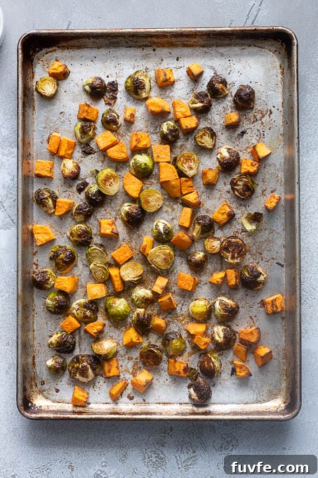 Roasted Winter Vegetables and Kale Salad 7 Brussels sprouts and sweet potatoes on a baking sheet after roasting.