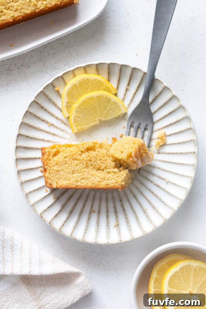 Slice of almond flour lemon loaf cake with glaze on a plate.
