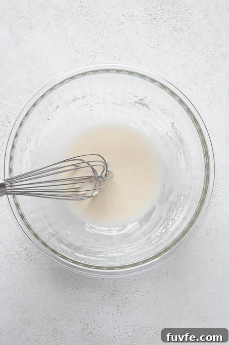 Glaze in mixing bowl for gluten-free lemon loaf.