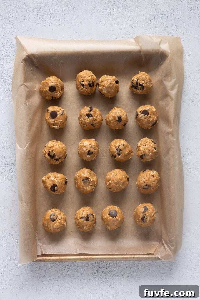 No-Bake Peanut Butter Protein Balls Recipe 7 Rolled peanut butter protein balls on a parchment lined baking sheet.