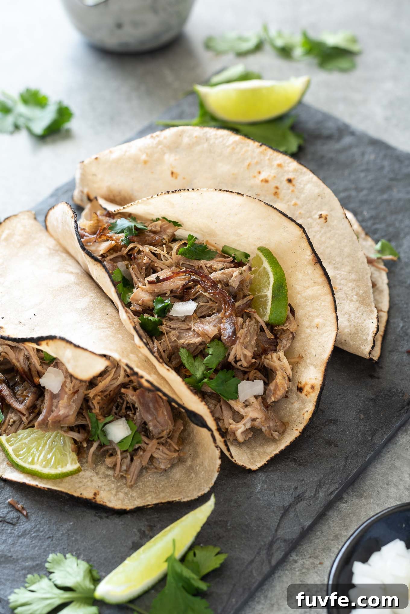 Slow Cooker Pork Carnitas in tortillas with onion, cilantro and lime