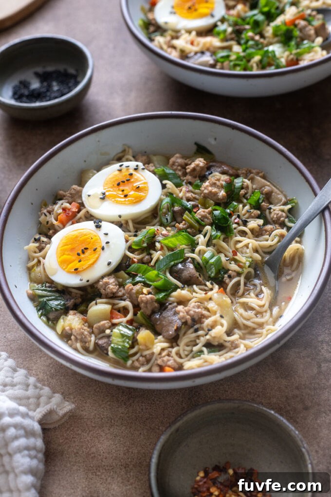 Close-up of brothy ground pork ramen with brown rice noodles and soft boiled egg.