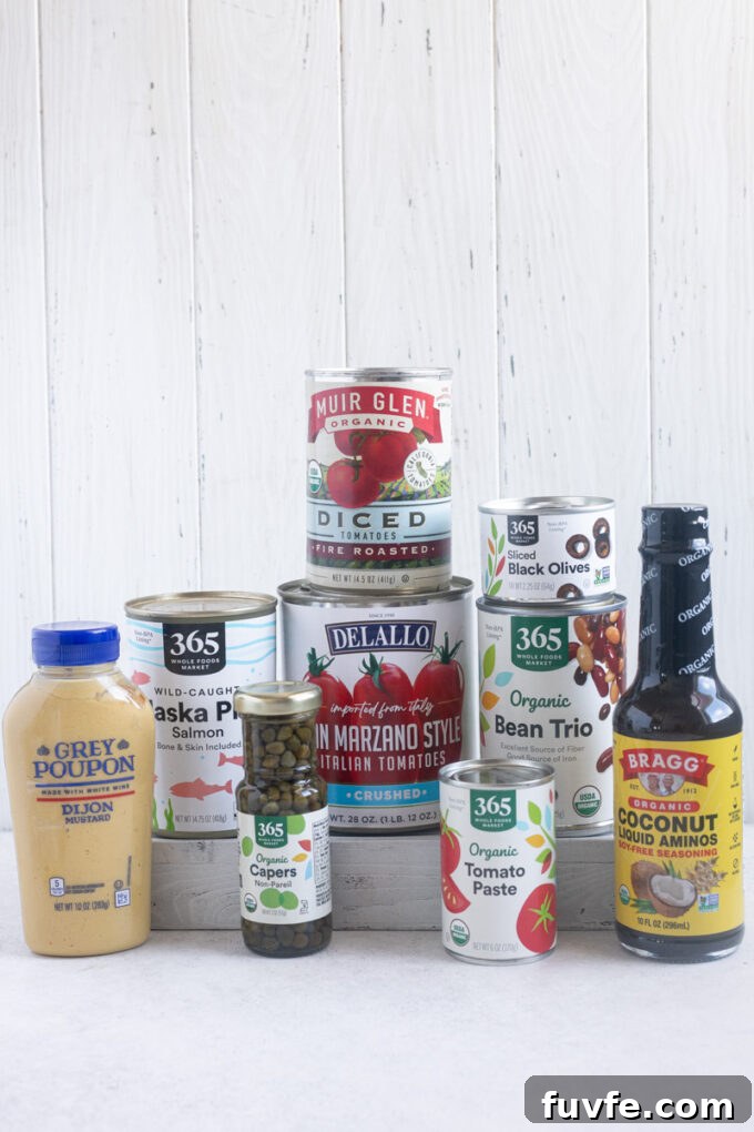 Pantry staples including tomato sauce, tomato paste, Dijon mustard and coconut aminos.