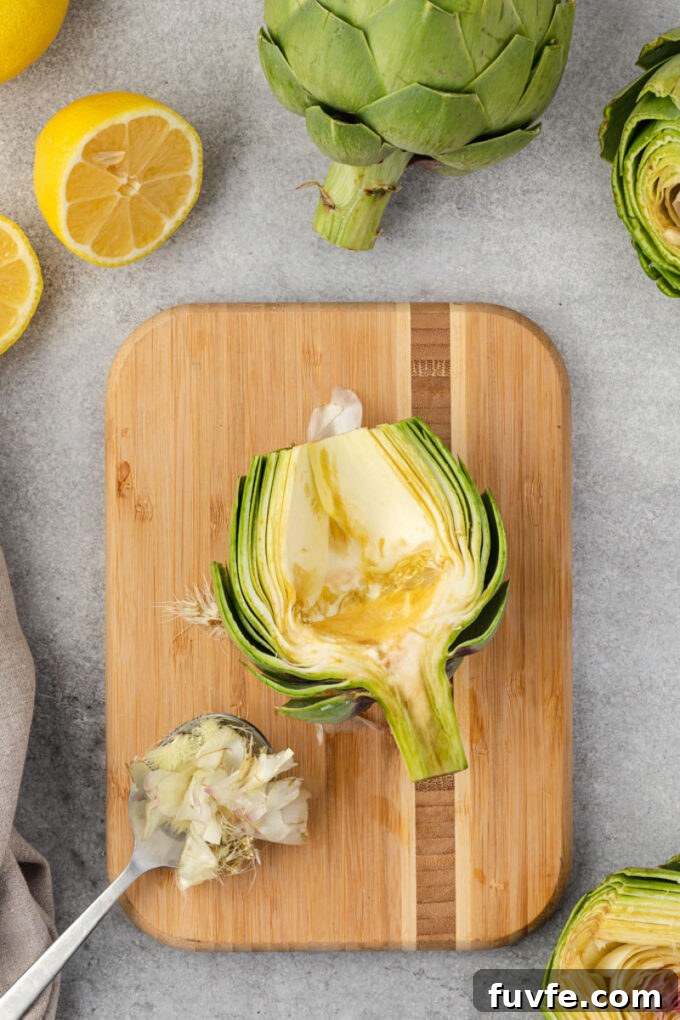 How to Trim and Prepare an Artichoke for Cooking 9 Scooping choke from artichoke with spoon.