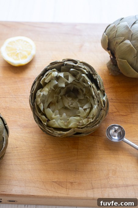 How to Cook Tender Instant Pot Artichokes 12 Steamed artichoke on cutting board with leaves separated.