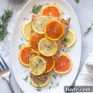 Slow roasted citrus salmon with lemon, orange slices and fresh dill on a baking dish.