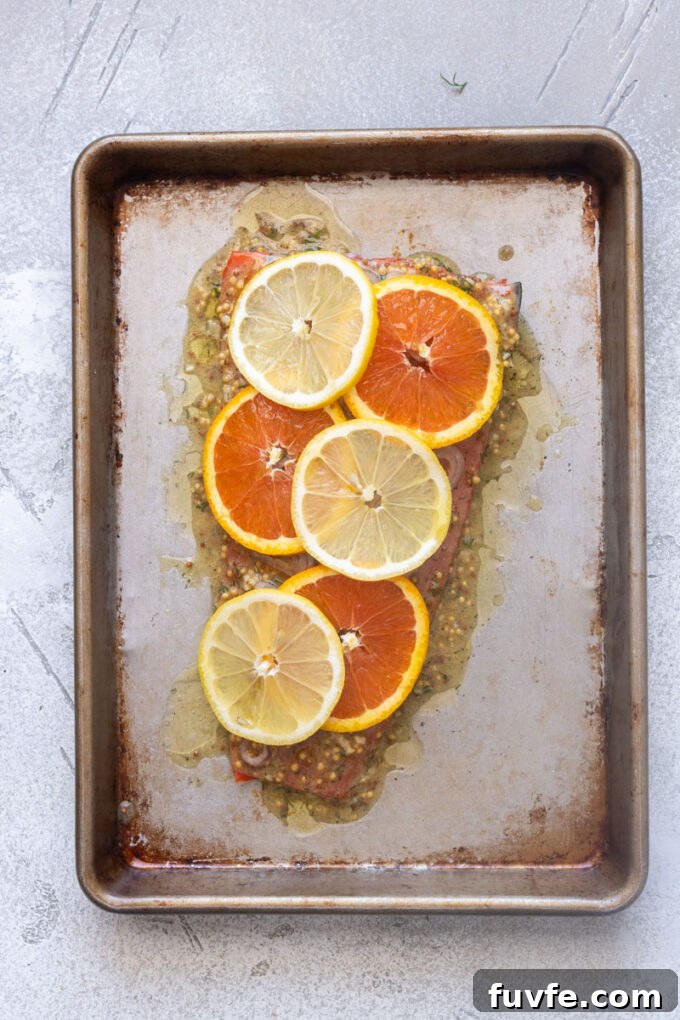 Salmon filet with citrus dijon sauce, sliced shallots and lemon and orange slices.