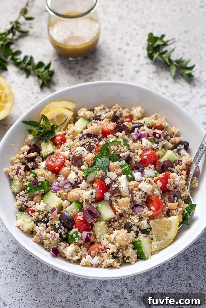 Greek quinoa salad in a bowl with spoon buried inside