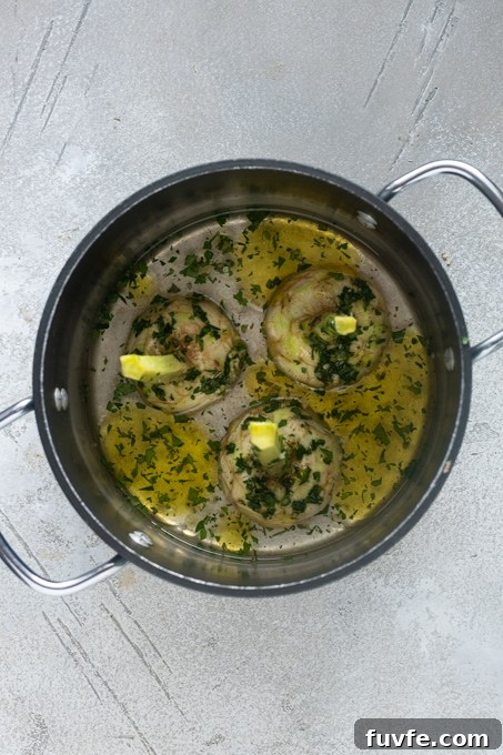 Roman artichokes in pot with garlic and herb mixture, olive oil and water.