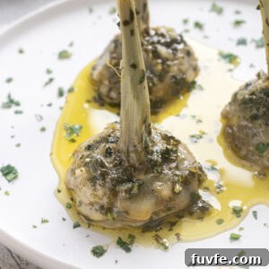 Carciofi alla Romana: Roman-Style Artichoke Recipe 15 Roman artichokes on serving plate with garlic, fresh herbs and olive oil.