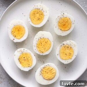 Air fryer hard boiled eggs cut in half with perfectly cooked yolks on a plate.