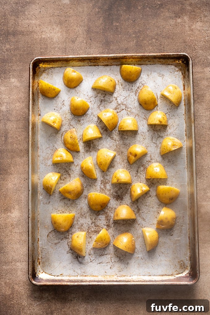 Halved baby gold potatoes on a baking sheet before roasting