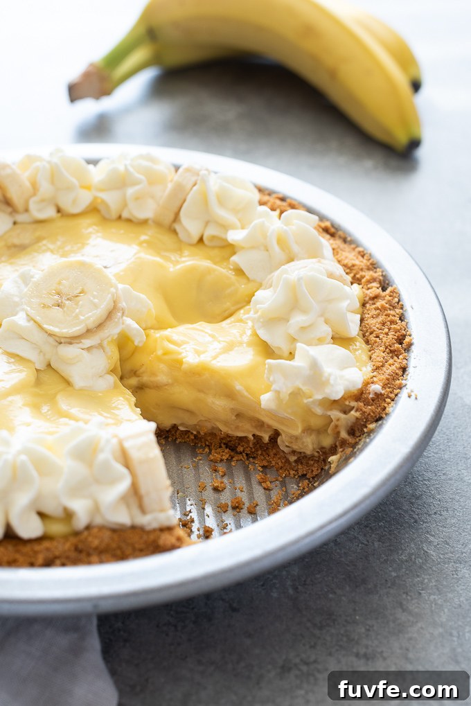 Banana Cream Pie Recipe with Graham Cracker Crust 8 Banana cream pie in pan with whipped cream and bananas on top