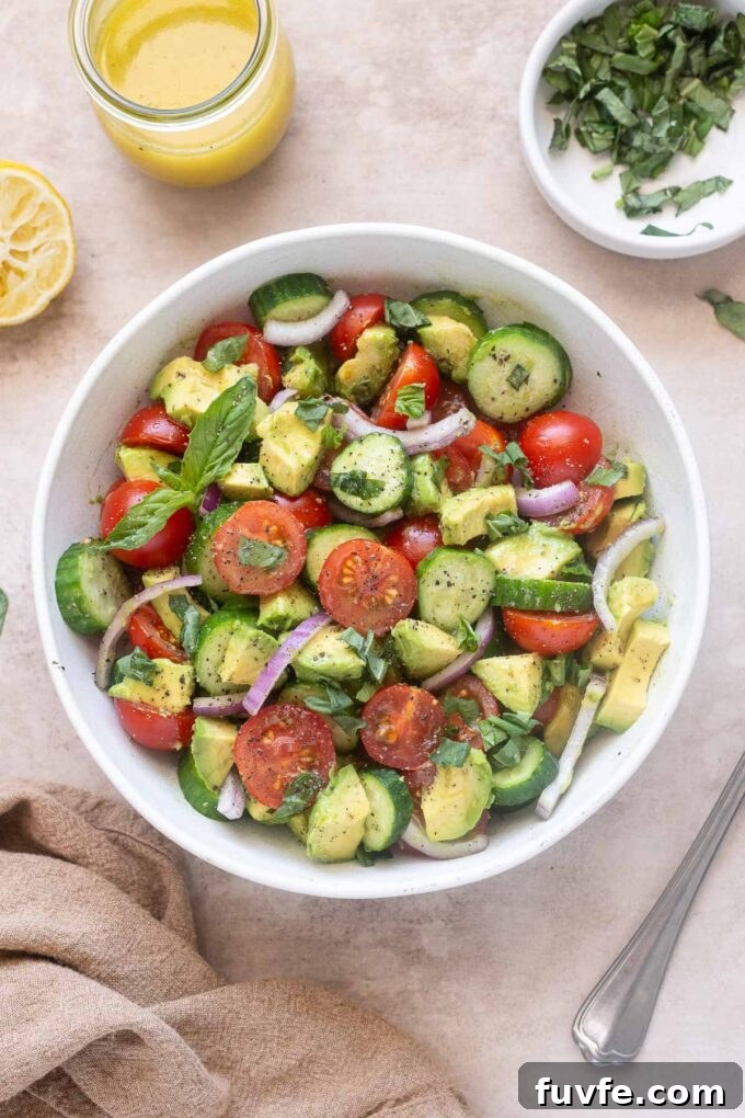 Avocado tomato and cucumber salad with basil and lemon vinaigrette in a serving bowl.
