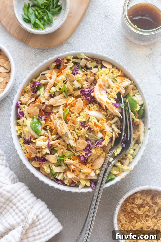 Chinese chicken salad with serving spoons digging into bowl.