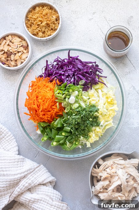 Chinese chicken salad ingredients sectioned in mixing bowl.