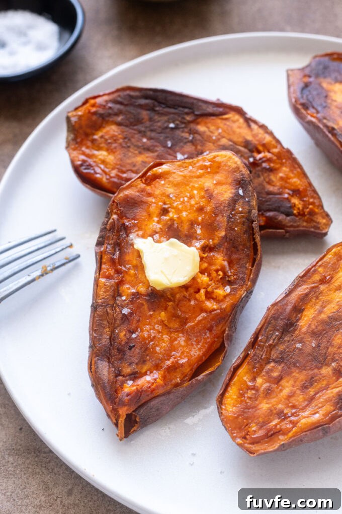 Baked sweet potato halves on a plate with butter and sea salt.