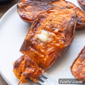 Caramelized roasted sweet potato halves with melted butter and flaky sea salt on a plate.