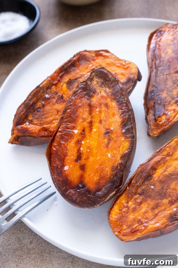 Roasted sweet potato halves with caramelized edges and sea salt on a plate.