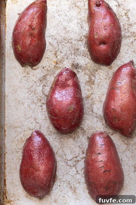 Sweet potatoes cut side down on baking sheet before roasting.
