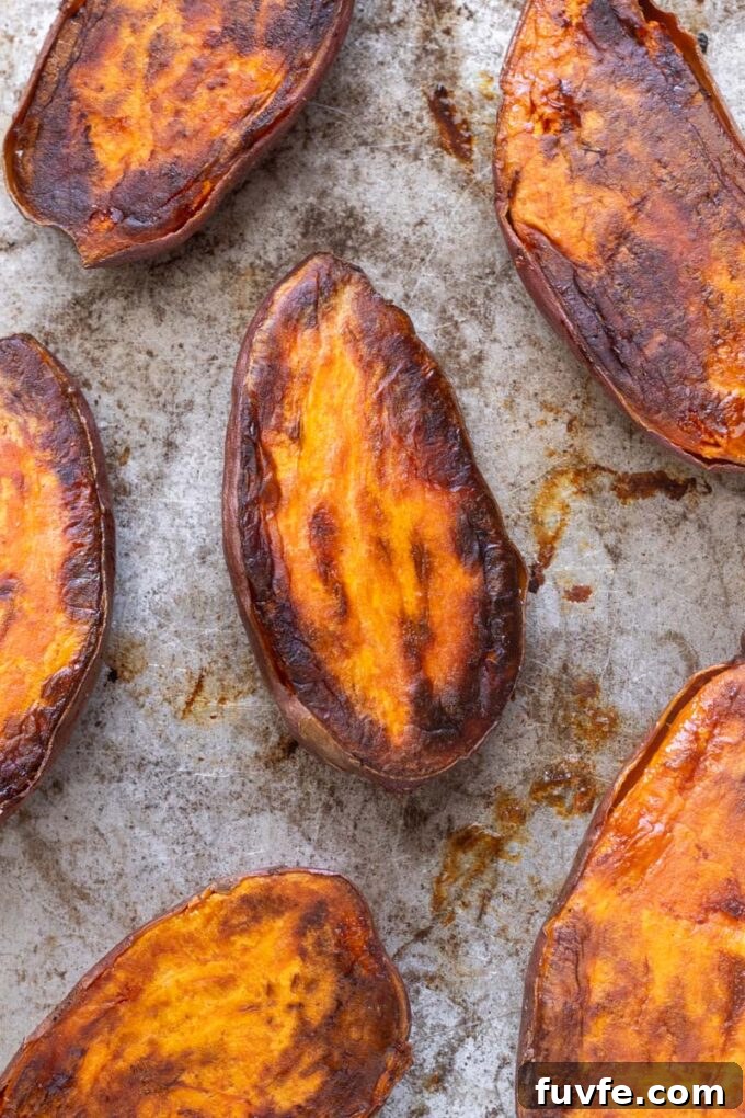 Caramelized roasted sweet potato halves on a baking sheet.